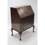 A walnut bureau with fitted interior enclosed by fall-front above three long graduated drawers &
