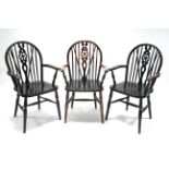 Three wheel-back carver dining chairs with hard seats, and on turned legs with spindle stretchers.