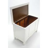 A white painted wooden blanket box with hinged lift-lid, panelled front, & on square supports,
