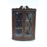 An oak hanging corner cabinet fitted two shelves enclosed by pair of leaded glazed doors, 27” wide x