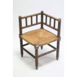 An early 20th century bobbin-frame corner chair with woven rush seat.