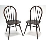 A pair of Ercol elm spindle-back dining chairs with hard seats, & on round tapered legs with spindle