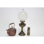 A brass oil table lamp with etched scroll design to the frosted glass globular shade; a copper