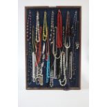 Approximately forty various necklaces displayed on a wall-mounted panel.