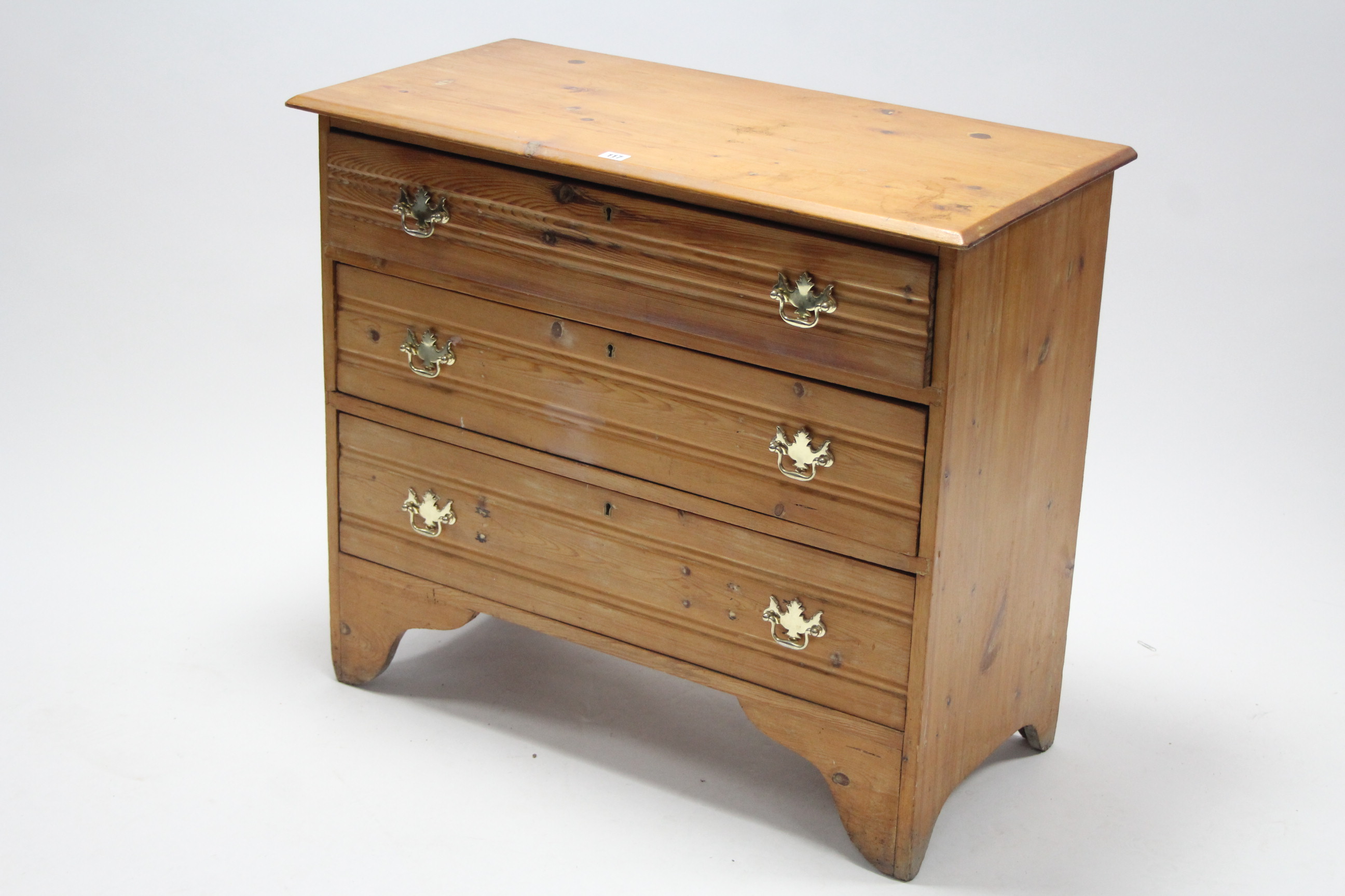 A pine small chest fitted three long graduated drawers with brass swing handles, & on bracket