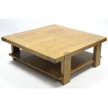 A light oak large square two-tier coffee table on square legs, 43½” wide x 15¾” high.