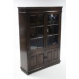 An oak standing bookcase, fitted two shelves enclosed by pair of glazed doors above cupboard