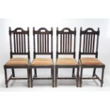 A set of four 1930's oak rail-back dining chairs with padded drop-in-seats and on barley-twist