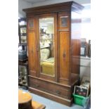 A late Victorian carved mahogany wardrobe enclosed by rectangular bevelled mirror door to centre