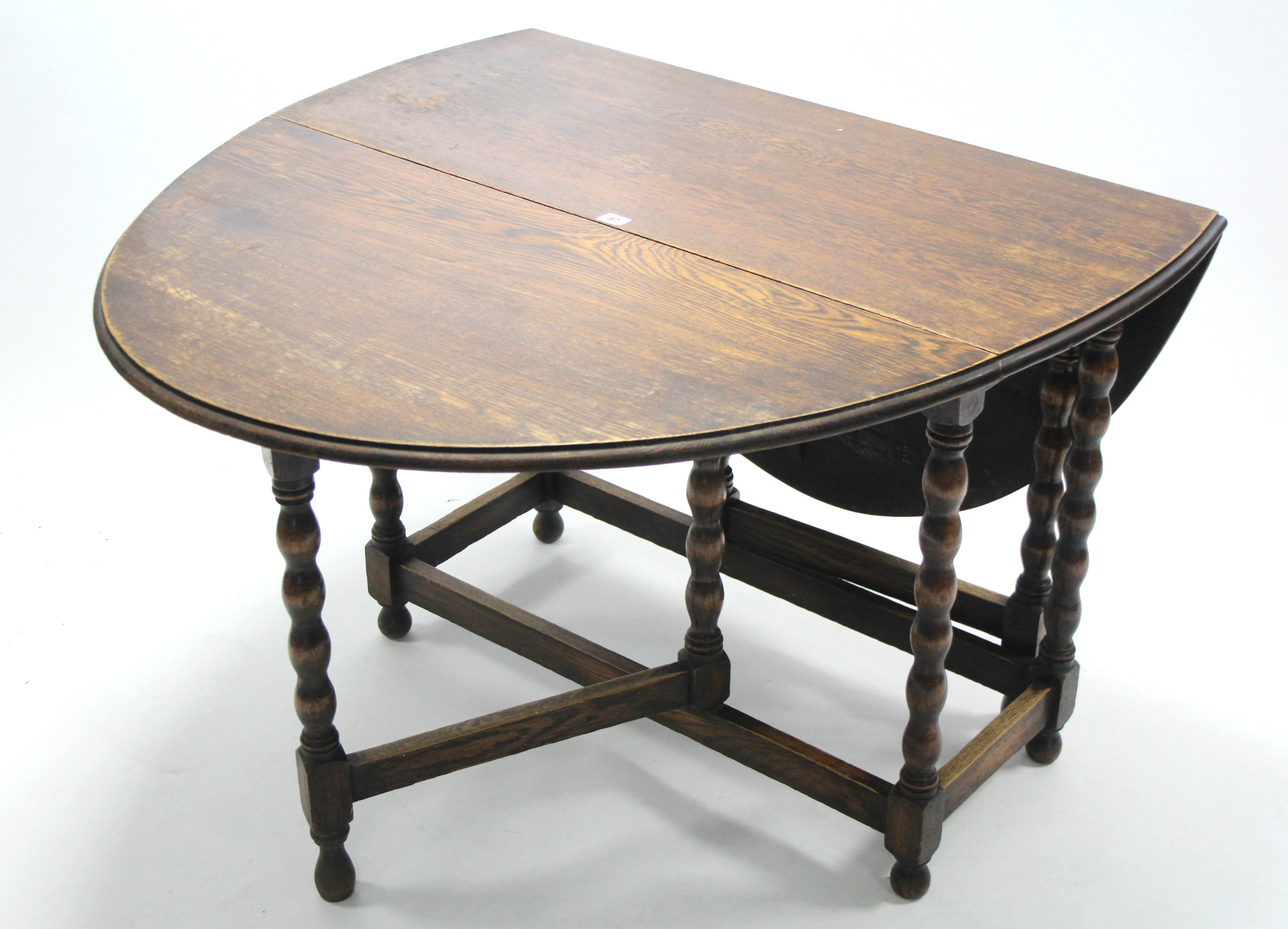 A 1930's oak oval gate-leg dining table on bobbin-turned legs and turned feet with plain stretchers,