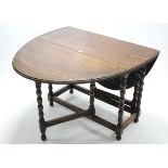 A 1930's oak oval gate-leg dining table on bobbin-turned legs and turned feet with plain stretchers,