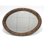 A composition frame oval wall mirror with raised fruit border and inset bevelled plate, 26" x 35".