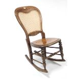 A late Victorian beech frame rocking chair inset woven-cane panel to back, with hard seat & on