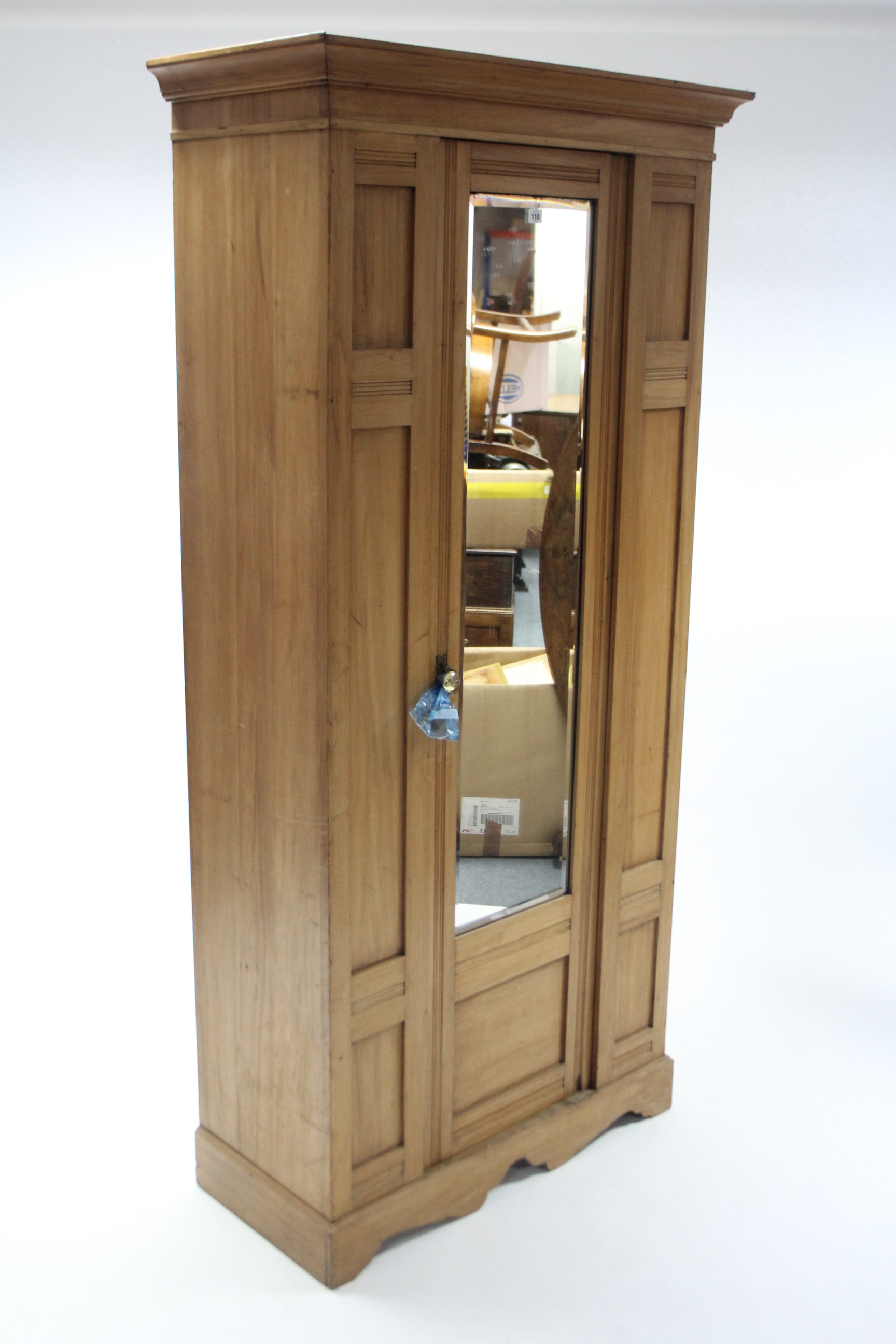 A late Victorian walnut wardrobe enclosed by rectangular mirror door to centre, and on shaped plinth