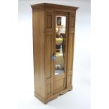 A late Victorian walnut wardrobe enclosed by rectangular mirror door to centre, and on shaped plinth