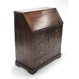 A 19th century oak bureau with fitted interior enclosed by fall-front above an arrangement of