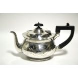 An oval teapot with bright-cut decoration, hinged lid, & ebonised handle; Birmingham 1912, by Levi &