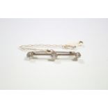 A yellow metal knife-edge bar brooch set three diamonds, the centre stone approximately 0.25 carats;