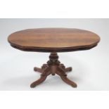 A late Victorian mahogany breakfast table, the shaped oval top on central turned & fluted column, on