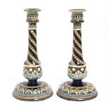 A pair of Doulton Lambeth stoneware candlesticks with round tapered columns &on circular domed
