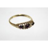 A late Victorian 18ct. gold ring set three graduated cabochon rubies with pairs of small diamonds in