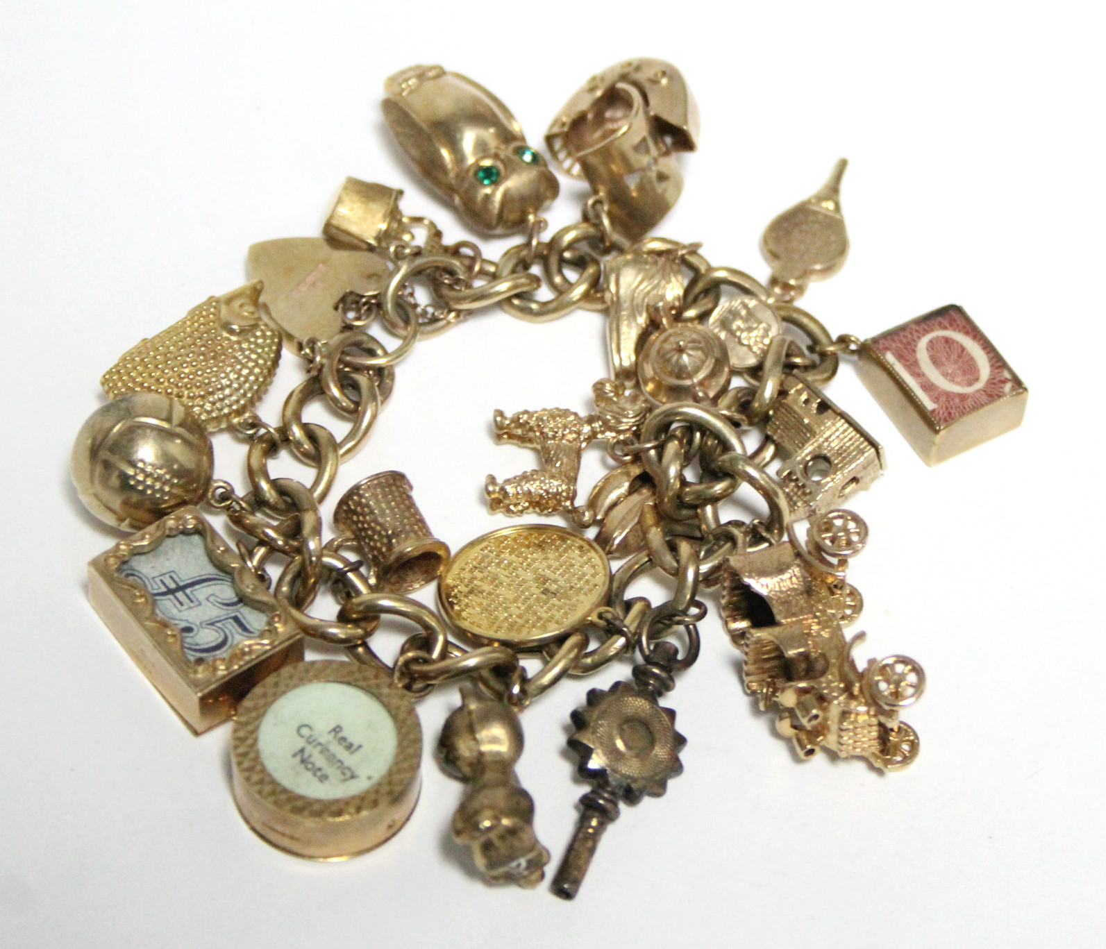 A 9ct. GOLD CURB-LINK CHARM BRACELET with nineteen hallmarked pendant charms & a gilt-metal watch