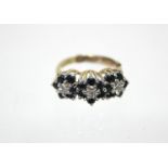 An 18ct. gold ring set three small diamonds, each within a border of small sapphires; London