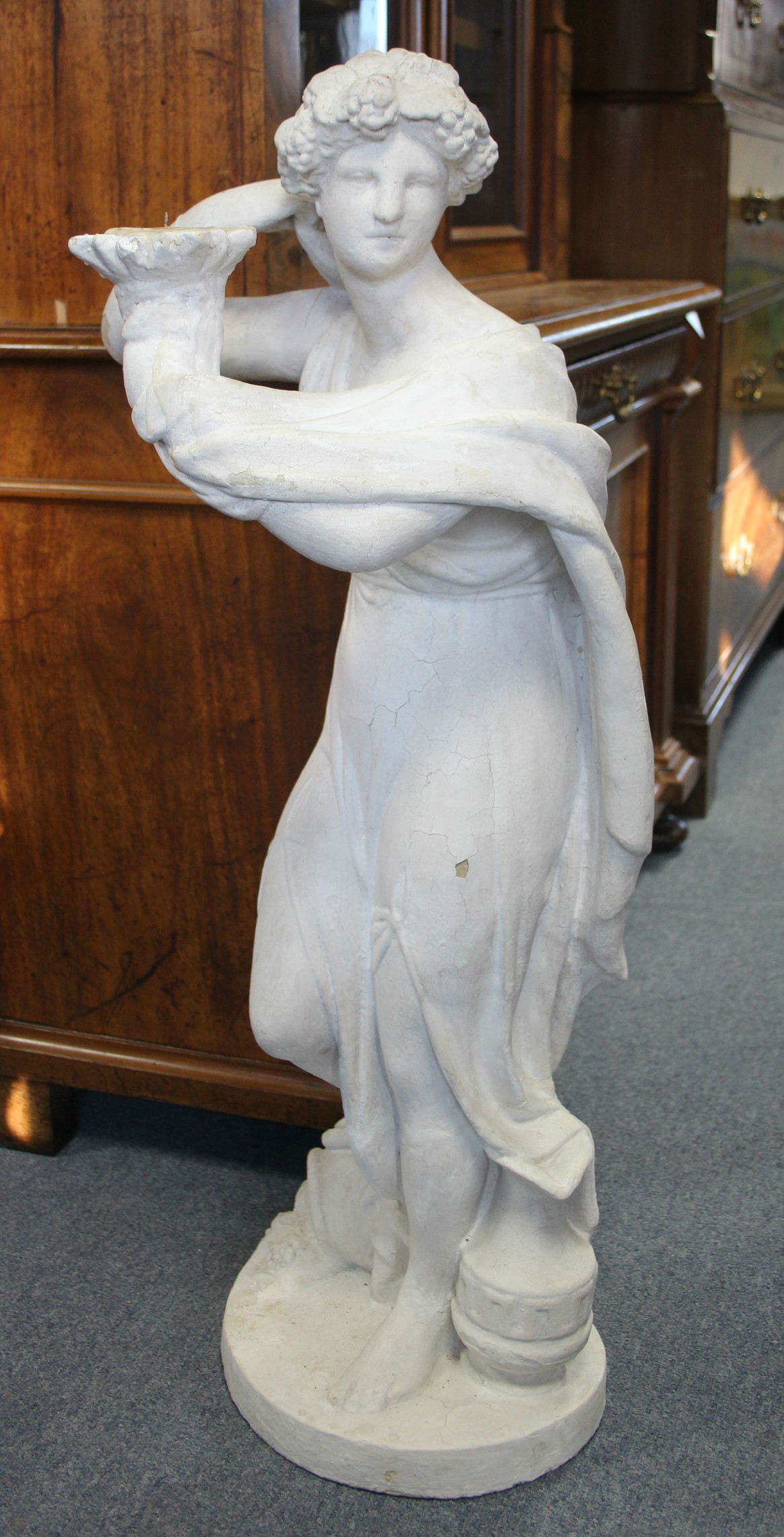 A white-painted plaster standing classical female figure with flowing robes, a candle holder to