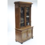 A late 19th century continental carved walnut bookcase, the upper part fitted three shelves enclosed