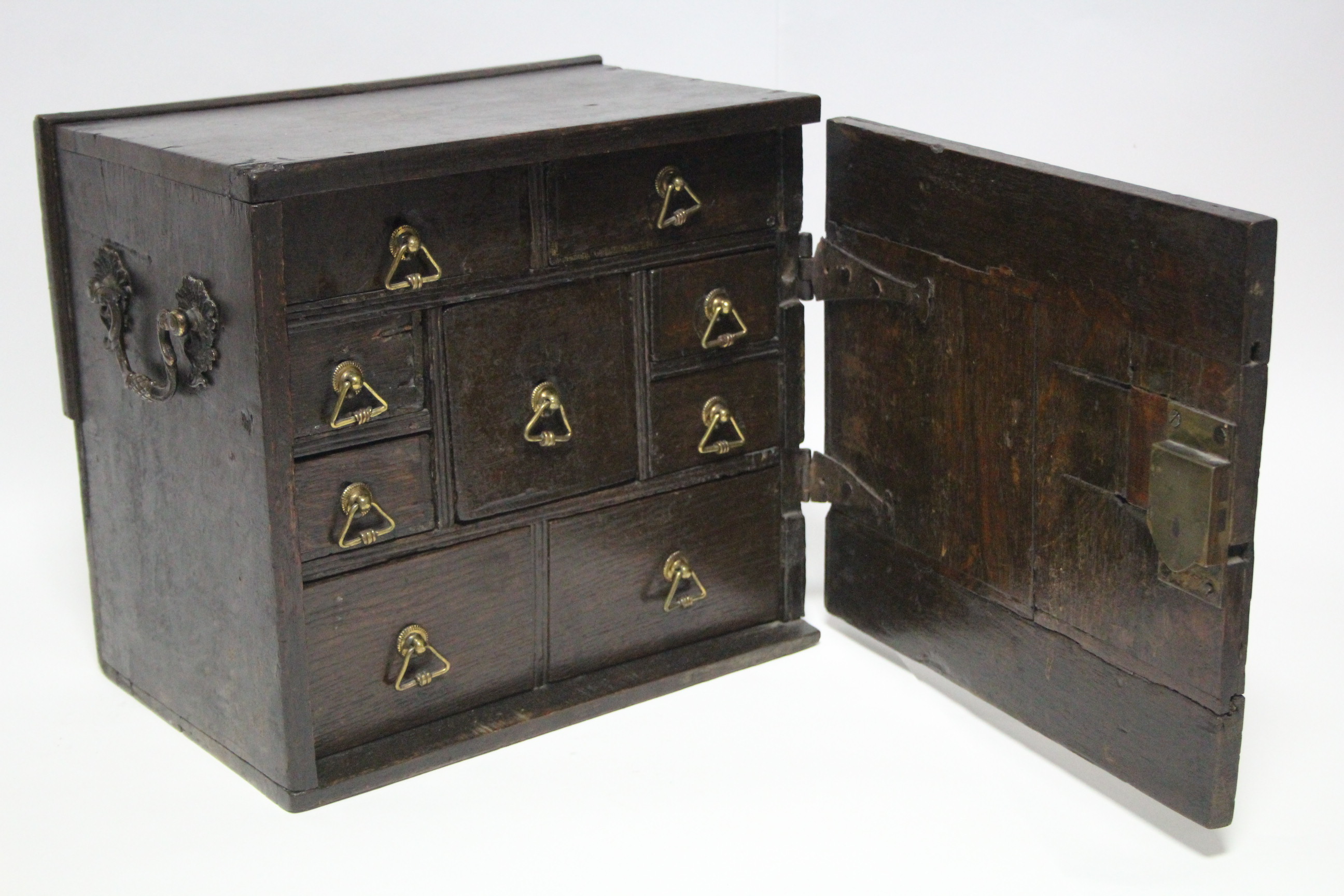 A late 17th/early 18th century oak small portable chest fitted with an arrangement of nine small