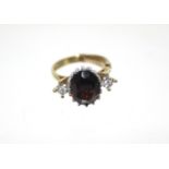 An 18ct. gold ring set large oval garnet, a small diamond either side; London hallmarks for 1975. (
