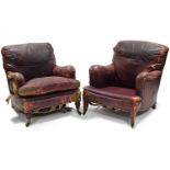A NEAR-PAIR OF EARLY 20th century LEATHER ARMCHAIRS BY HOWARD & SONS of LONDON, of burgundy