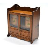 An oak hanging smoker’s cabinet fitted central recess for tobacco jar, flanked by four drawers