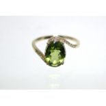 A PERIDOT & DIAMOND RING, the oval peridot measuring approx. 9mm x 8mm, set within borders of