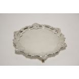 An Edwardian card tray with raised shell-&-scroll border, on three pad feet, 6½” diam., London 1906,