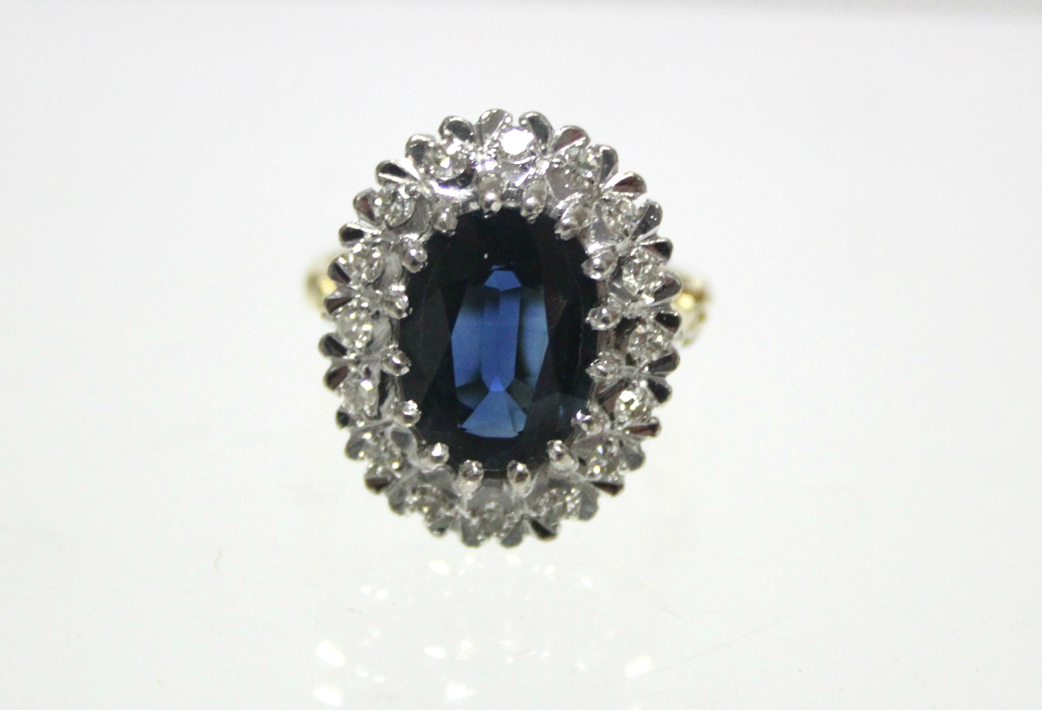 An 18ct. gold ring set oval sapphire within a border of small diamonds; London hallmarks for