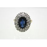 An 18ct. gold ring set oval sapphire within a border of small diamonds; London hallmarks for