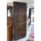 An 18th century oak standing corner cupboard with three shaped shelves to the top enclosed by
