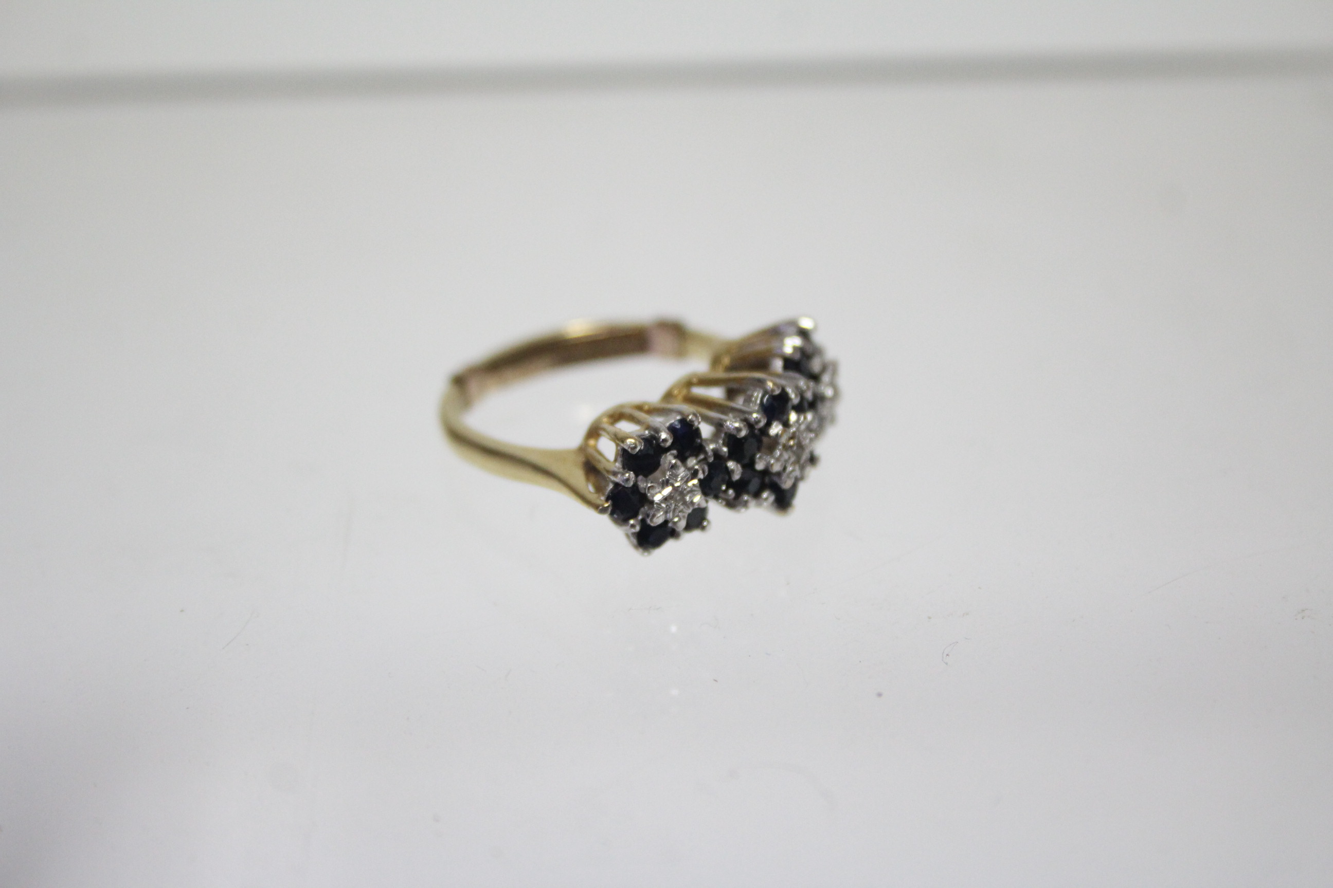 An 18ct. gold ring set three small diamonds, each within a border of small sapphires; London - Image 2 of 3