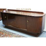 A mahogany Art Deco style sideboard with curved ends, the large central cupboard with two shelves