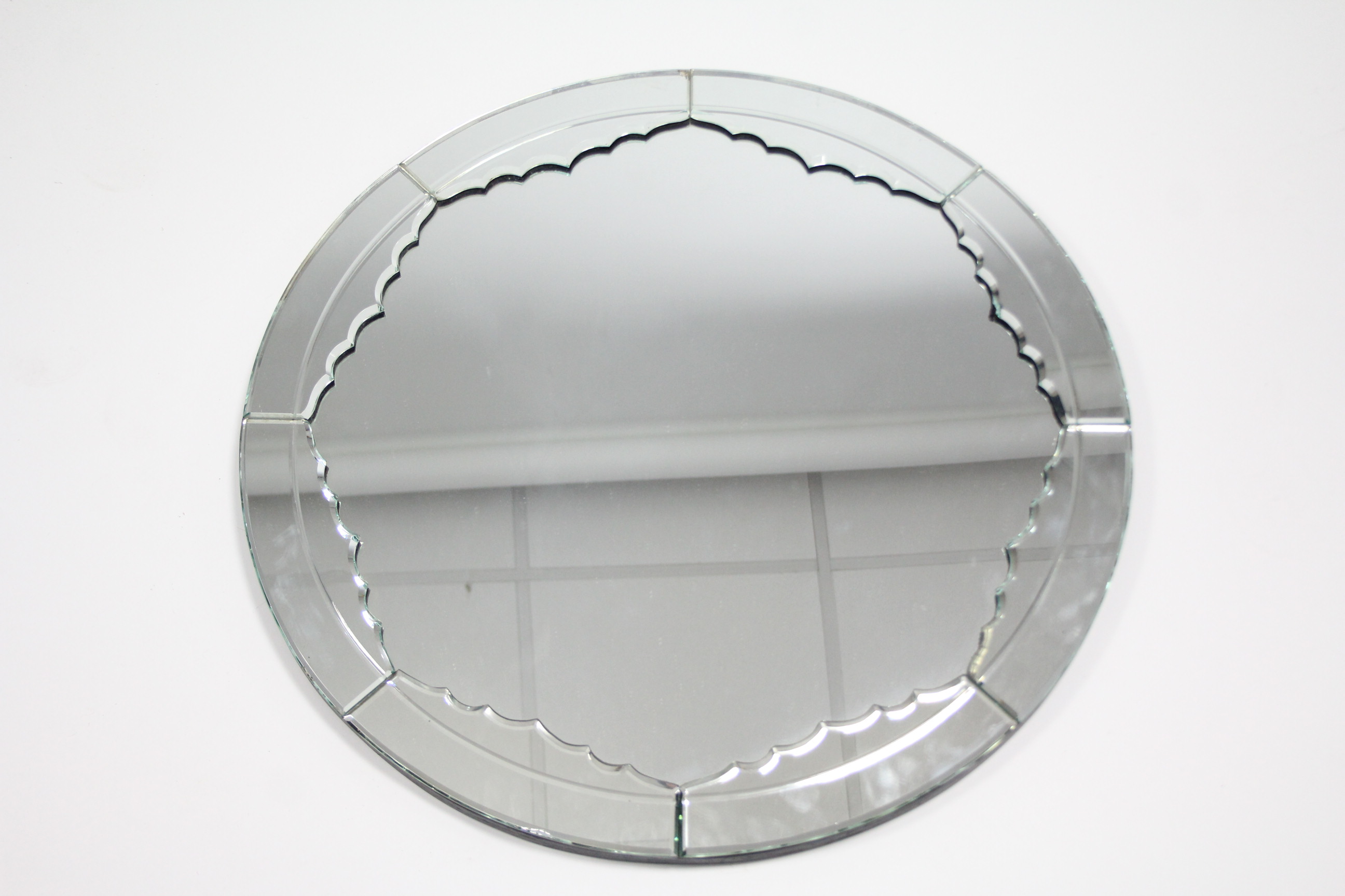 A 1920s/30s circular wall mirror, the segmented mirrored border with bevelled edges; 27” diam.