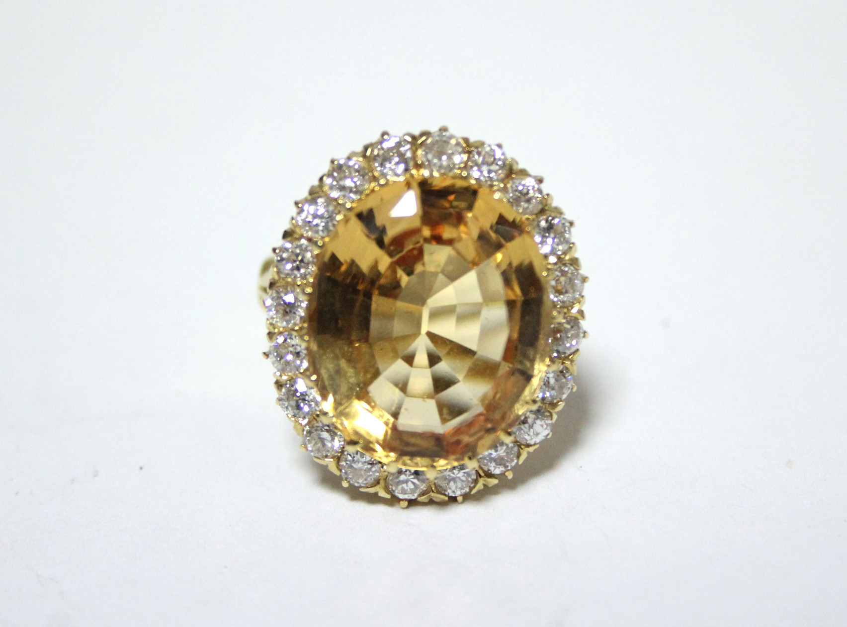 AN 18ct. GOLD, TOPAZ, & DIAMOND RING, the large oval topaz measuring approx. 19mm x 15mm, set within