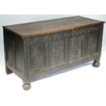 A late 17th century oak coffer with hinged lid above the carved four-panel front, on later carved