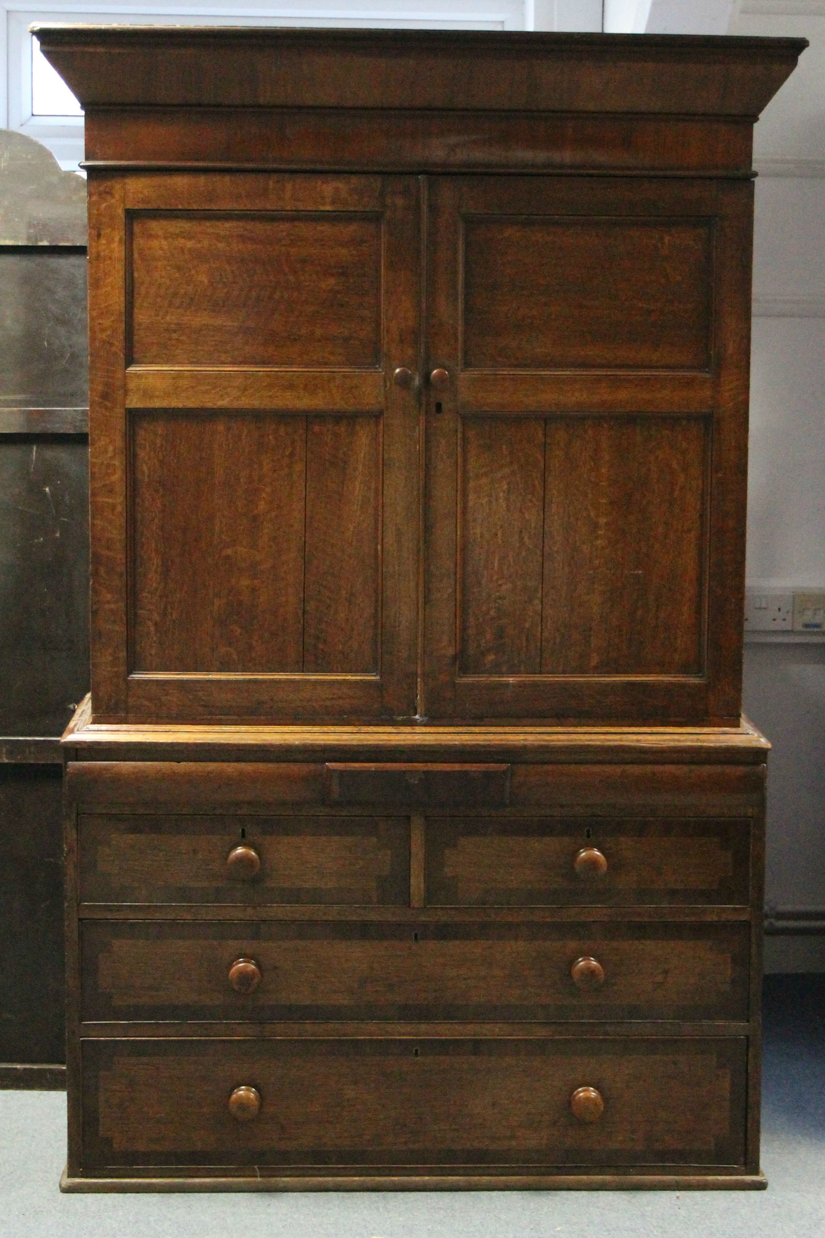 An early 19th century provincial oak & mahogany linen press, the upper part fitted three shelves