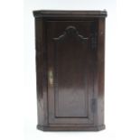 An 18th century oak narrow hanging corner cupboard with three shaped shelves to the interior