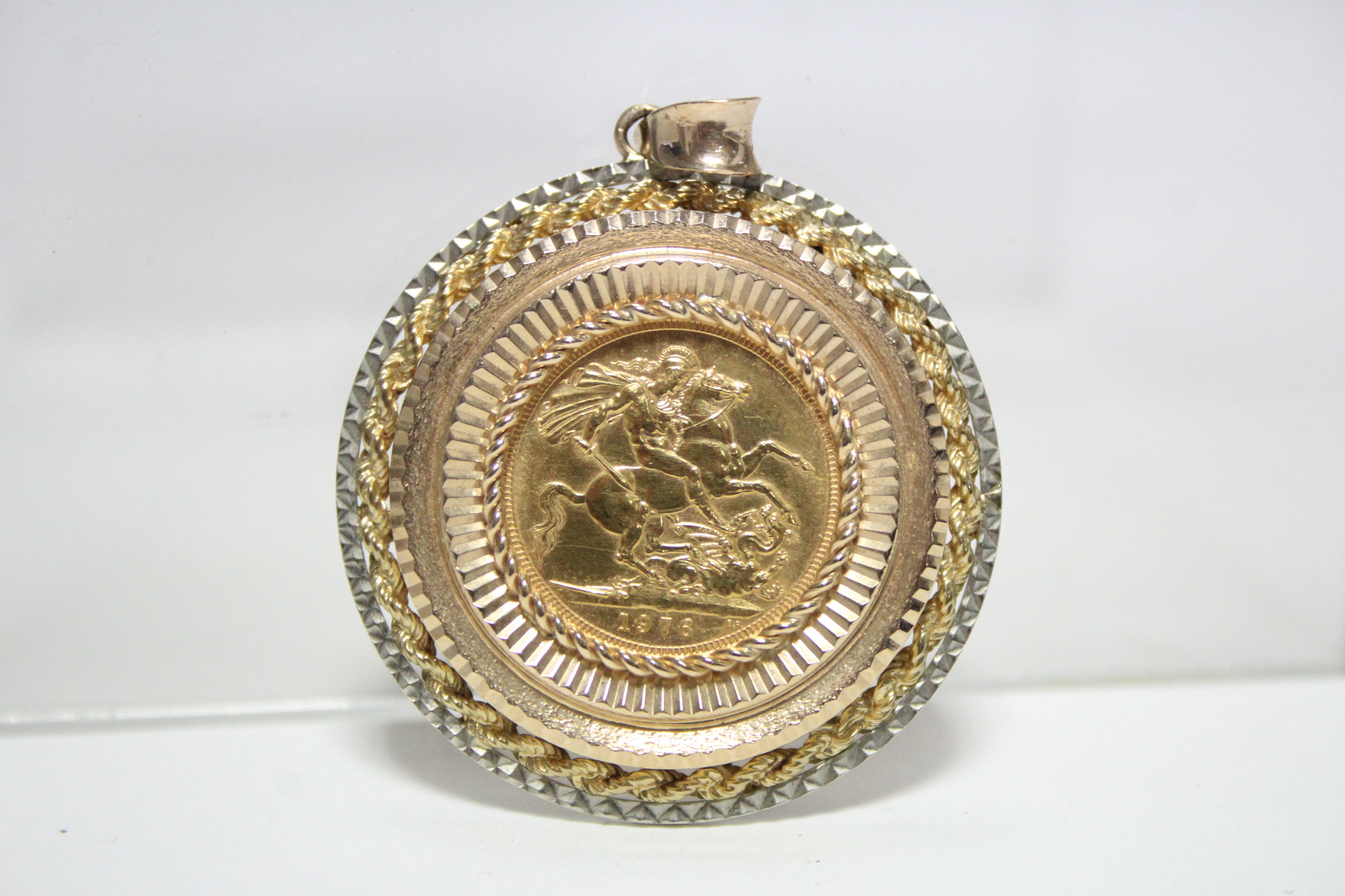 A 1976 Sovereign, loose-mounted as a pendant within a 9ct. yellow & white gold border.