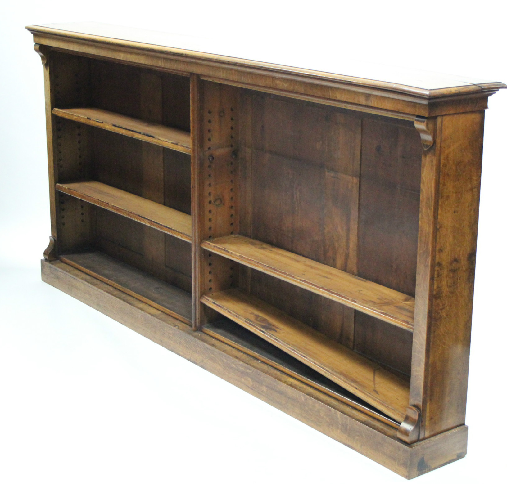 An early 19th century light oak standing open bookcase, having four adjustable shelves, plain scroll