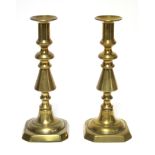 A pair of late 19th/early 20th century brass candlesticks, on turned tapering columns & square