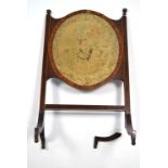 A rosewood & mahogany small firescreen inset oval floral needlework panel to the centre, on four