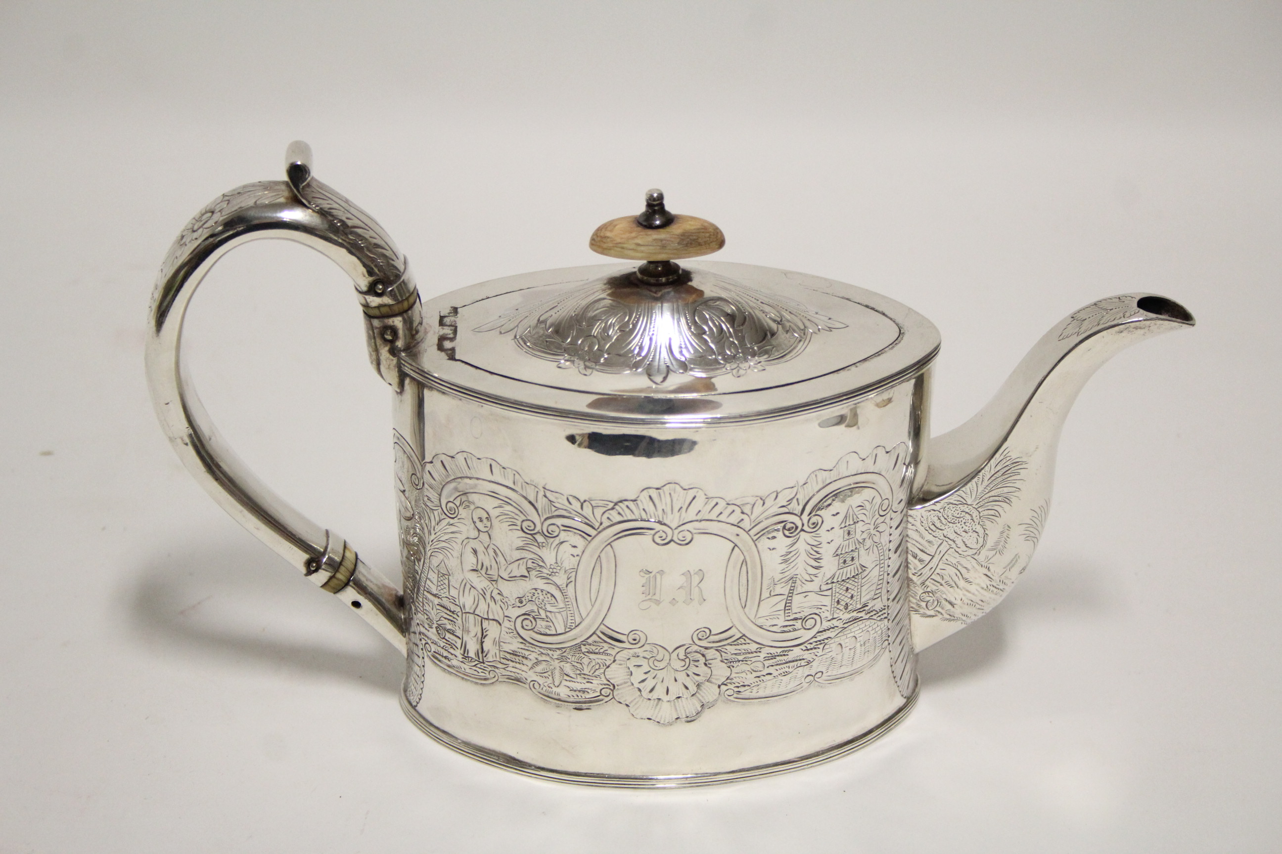 A George III oval straight-sided teapot with repoussé Chinoiserie decoration; London 1794, by